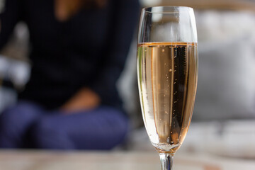 Closeup on sparkling rose wine glass and blurred woman on background. Friends meeting, party celebration concepts