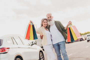 Poster - Photo of retired pensioner wife husband grey haired old couple hold many bags car park outside outdoors in urban city