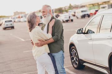 Wall Mural - Photo of attractive charming pensioner grandmother grandfather dressed shirts smiling embracing riding auto outdoors urban city street