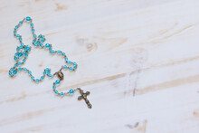 Rosary With Crystal Blue Beads On A White Wood Background With Copy Space