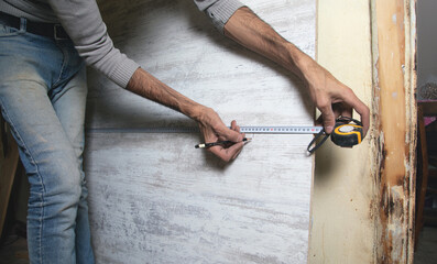 Wall Mural - Carpenter marking laminate with tape measure and pencil.