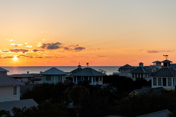 Wall Mural - Aerial view on colorful yellow sunset sun with ocean landscape of Gulf of Mexico in Seaside, Florida from rooftop terrace buildings houses cityscape and weather vanes
