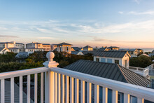 Sunset In Seaside, Florida Gulf Of Mexico, View From Wooden Rooftop Terrace Balcony Building With Houses Cityscape And White Railing Balustrade Ball Top Finial