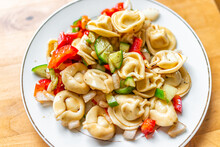 Tortellini Cheese Filled Pasta Salad On Table Above Flat Top View With Sliced Cucumbers, Red Bell Peppers And Seasoning On White Plate As Healthy Food
