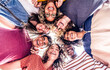 canvas print picture - Multicultural group of young people standing in circle and smiling at camera - Happy diverse friends having fun hugging together - Low angle view.