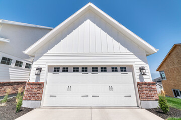 Wall Mural - Exterior of a garage with white wood and red bricks siding