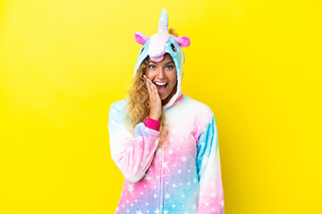 Wall Mural - Girl with curly hair wearing a unicorn pajama isolated on yellow background with surprise and shocked facial expression