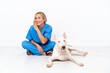 Young veterinarian English woman sitting on the floor with dog whispering something