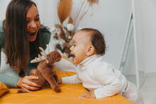 A Young Mother With A Baby, Relaxing And Playing Together In Bed, A Lazy Morning, A Warm And Cozy Scene. Selective Focus.