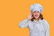 © Андрей Журавлев - Happy woman chef holding her ear and listening on yellow studio background, copy space