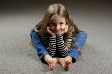 The European girl is sitting on the ground. Bare feet. long hair. The schoolgirl is tired.