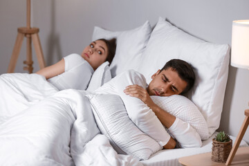 Canvas Print - Upset young man lying in bed after quarrel with his wife