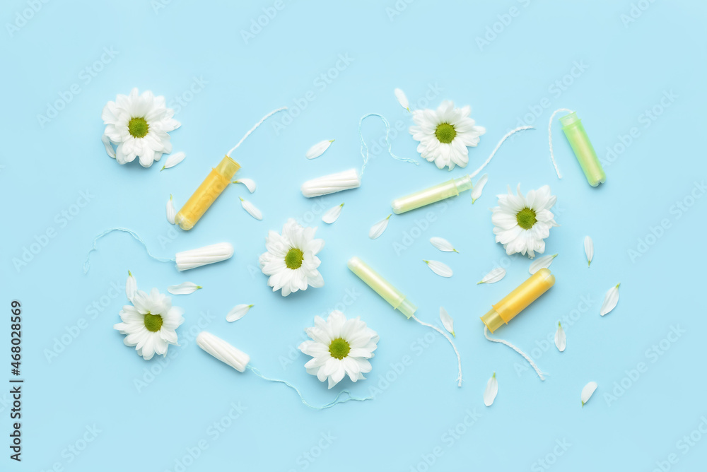 Menstrual tampons and flowers on blue background