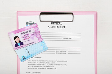 Poster - Clipboard with rental agreement and driver licenses on white wooden background, closeup