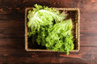 Basket with fresh lettuce on wooden background