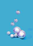 Fototapeta Dmuchawce - Shiny holographic Christmas balls on pastel blue background, others are falling from above. Festive trendy flashy New Year celebration creative concept. Design for fashion advertisement or banner.