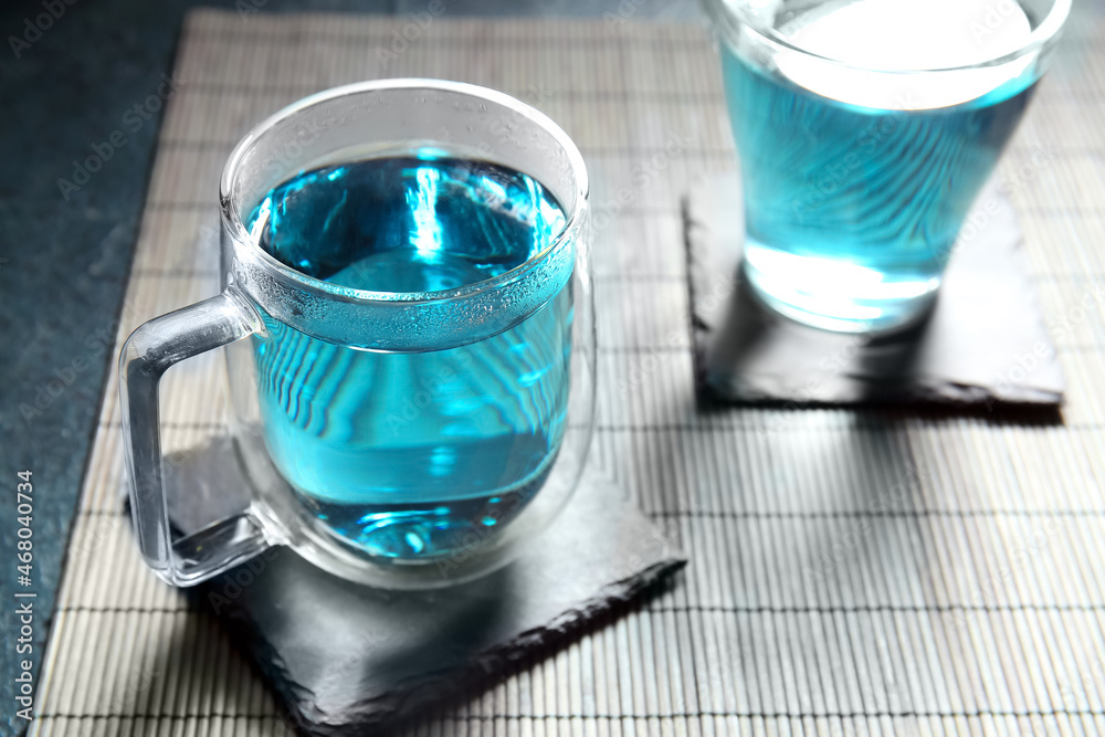 Glass cups of organic blue tea on table, closeup