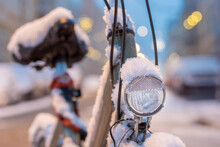Selective Focus Shot Of A Front Light Of A Parked Bicycle On The Street Covered With Snow