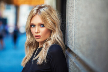 Wall Mural - Attractive young blonde girl walking in long black evening dress outdoors