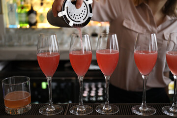 Sticker - Closeup shot of a bartender filling a cocktail into the glasses