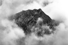 Top Of A Mountain Emerging From The Clouds In Grayscale