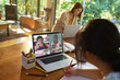 © vectorfusionart - Asian girl using laptop for video call, with smiling diverse elementary school pupils on screen