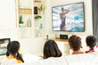© vectorfusionart - Rear view of family sitting at home together watching swimming competition on tv