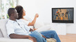 Rear view of african american couple sitting at home together watching basketball match on tv