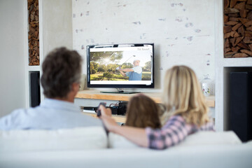 Canvas Print - Rear view of family sitting at home together watching golf event on tv