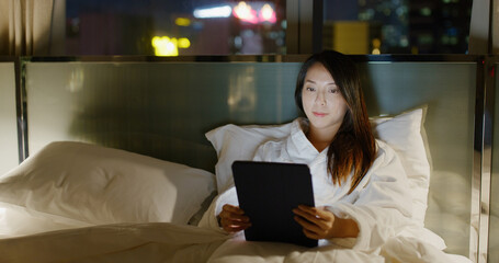 Poster - Woman use of tablet computer on and lying on bed at night