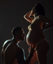 Pregnant Woman With Husband. Couple In Love, Sensual Lovers Hugging And Embracing.