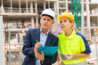 © JackF - Foreman in suit and white hardhat discussing project documentation while staning in cosntruction area.