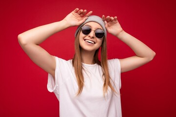 Wall Mural - Portrait photo of young emotional positive happy smiling funny laughing beautiful attractive dark blonde woman with sincere emotions wearing casual white t-shirt with empty space for mockup, grey hat