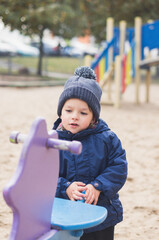 Canvas Print - Close up of a cute Caucasian child with a winter outfit standing outdoors near a colored gane