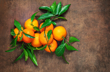 Wall Mural - Mandarines oranges fruits or tangerines with green leaves on a wooden table. Copyspace. Fresh picked mandarins T