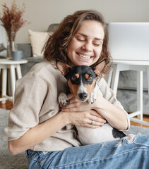 Wall Mural - Young woman hugging her cute basenji dog at home. Love and care pet