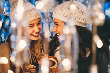 Wall Mural - happy women friends having fun, enjoying moments together in christmas decorated background.