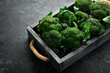 Fresh green broccoli in a wooden box. Top view. On a black background.