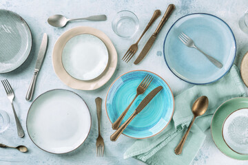 Modern tableware set with cutlery and a vibrant blue plate, overhead flat lay shot