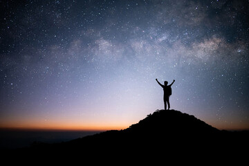 Wall Mural - Silhouette of young traveler and backpacker standing and open arm and watched the star and milky way alone on top of the mountain. He enjoyed traveling and was successful when he reached the summit.