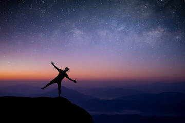 Wall Mural - Silhouette of young traveler and backpacker standing and open arm looking the star and Milky Way alone on top of the mountain. He enjoyed traveling and was successful when he reached the summit.