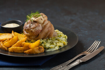 Wall Mural - Boiled knuckle, served with cabbage and baked potatoes. Front view. Darkblue background. Dark mod.