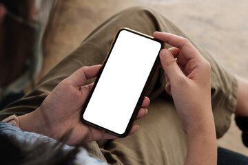 Top view woman with mask sitting and holding blank screen mock up mobile phone.
