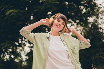 Canvas Print - Photo of funny funky young woman wear green shirt earphones smiling listening songs walking outside city street