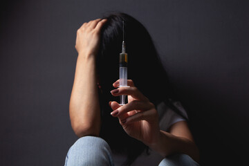 Wall Mural - Girl holding syringe with drugs while sitting on the floor