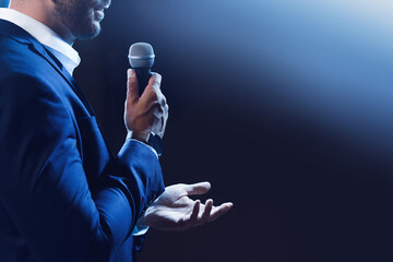 Wall Mural - Motivational speaker with microphone performing on stage, closeup. Space for text
