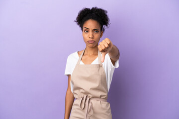 Sticker - Restaurant waiter latin woman isolated on purple background showing thumb down with negative expression