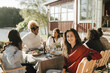 © Maskot - Portrait of woman with female friends eating during party on sunny day