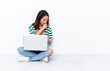 © luismolinero - Young Vietnamese woman with a laptop sitting on the floor isolated on white wall is suffering with cough and feeling bad