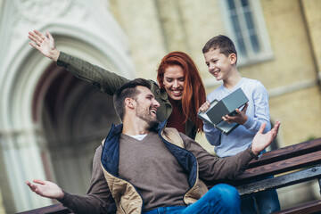 Wall Mural - Young family with present outdoor.Mother and son giving a gift box to father.